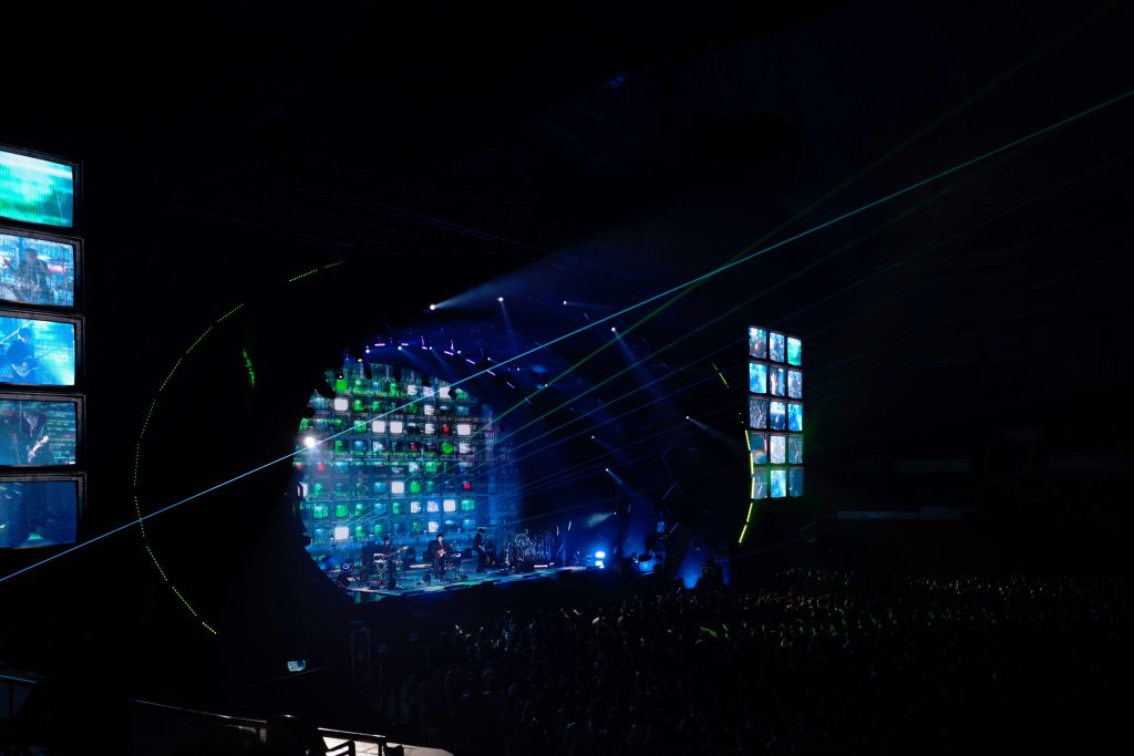 Escenario de concierto con pantallas LED modulares formando estructuras visuales dinámicas, efectos de luz y proyecciones digitales en directo